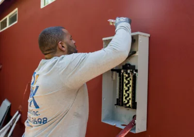 Electrician installing a circuit breaker on a red wall.